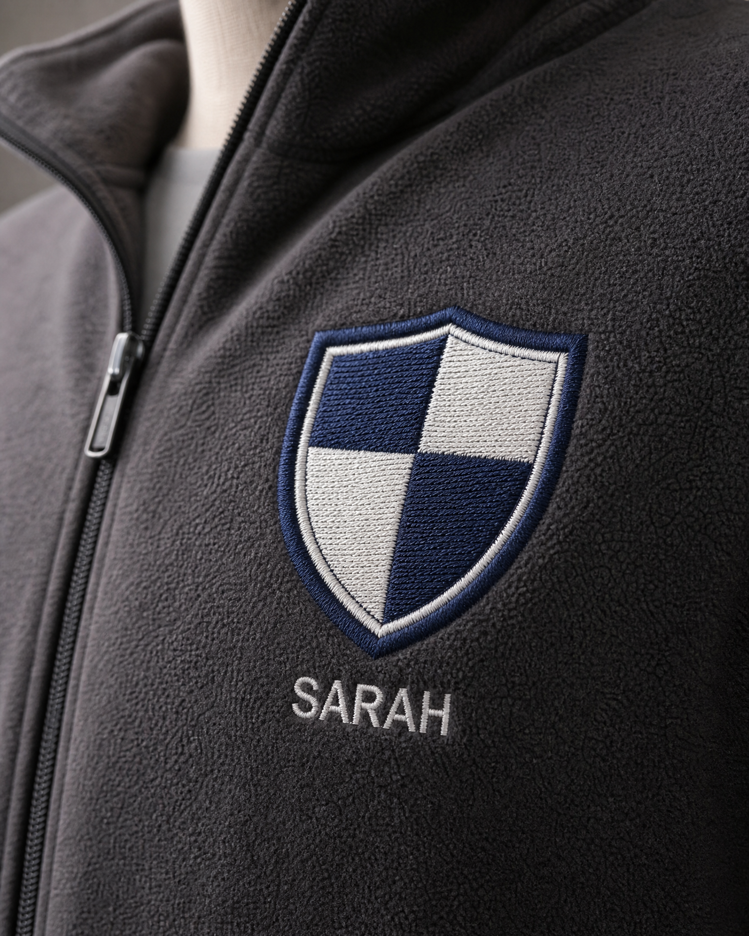 Close-up of a black fleece jacket with an embroidered company logo and personalised employee name.