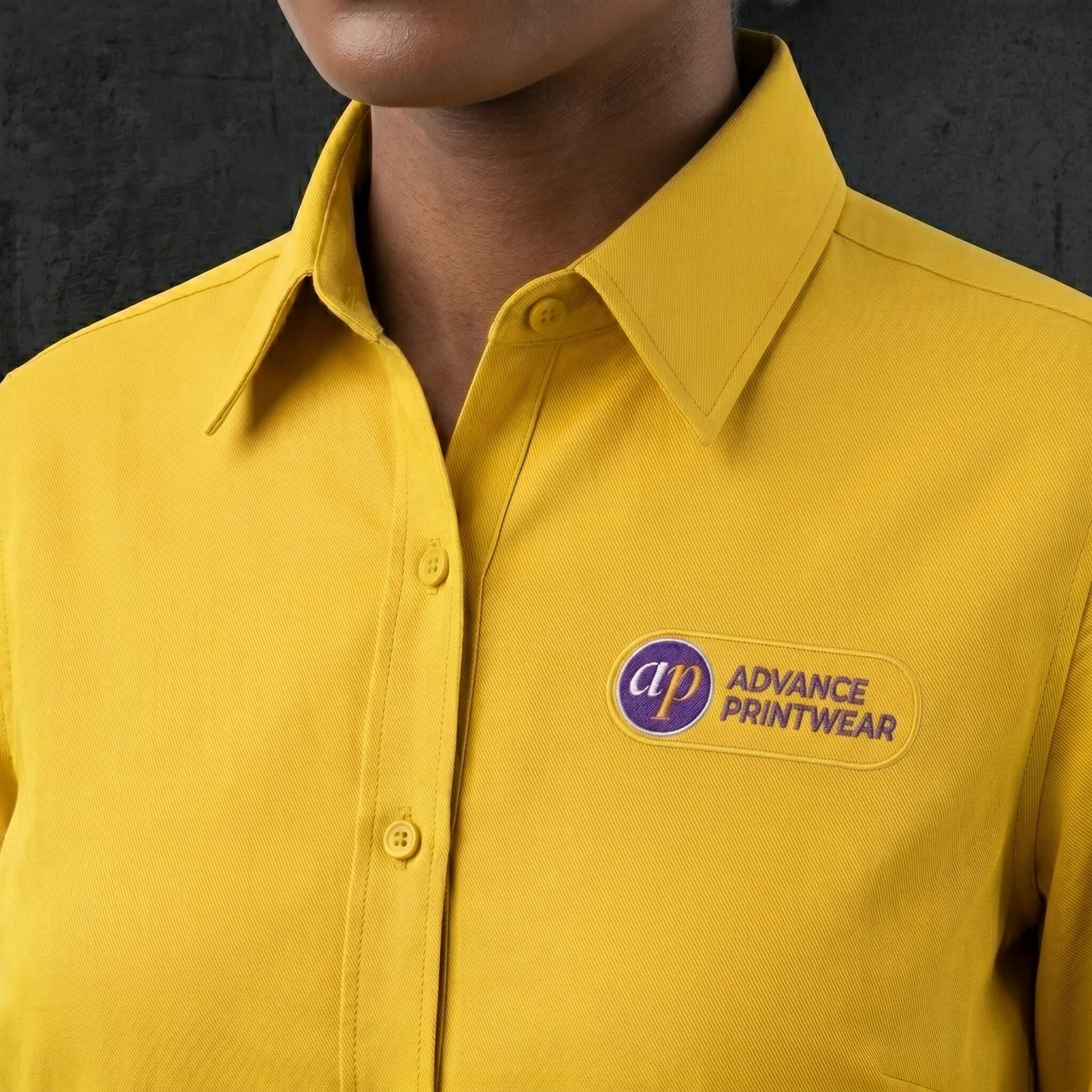 embroidered logo on a yellow uniform shirt in purple and yellow